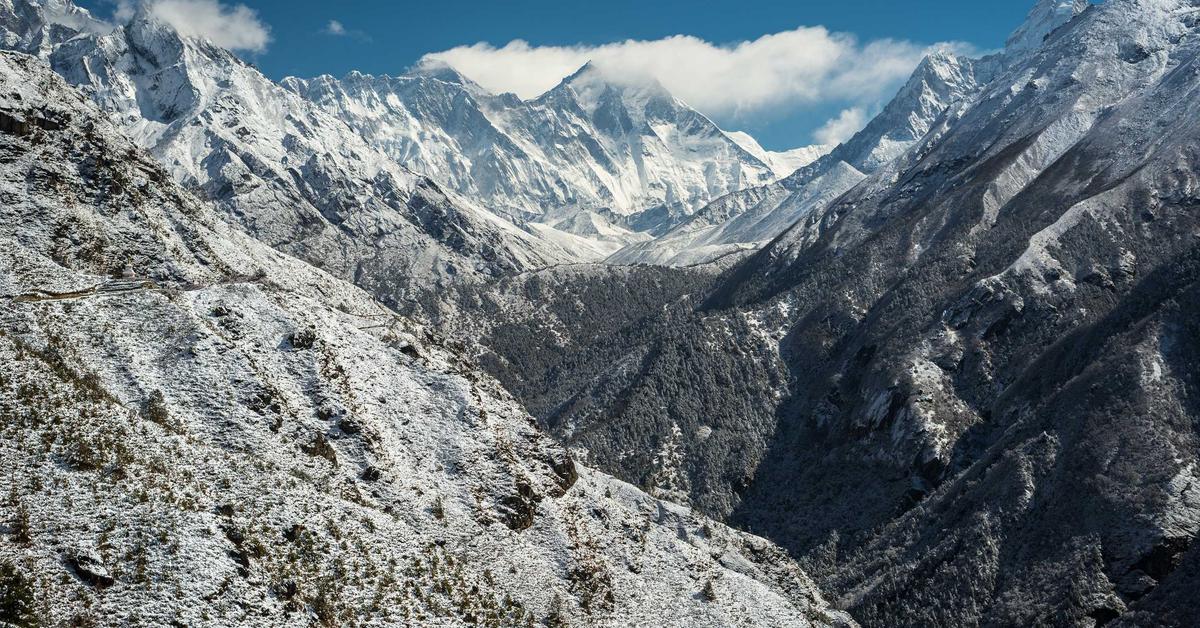 Snow-covered alpine valley with jagged peaks under a blue sky in winter light.