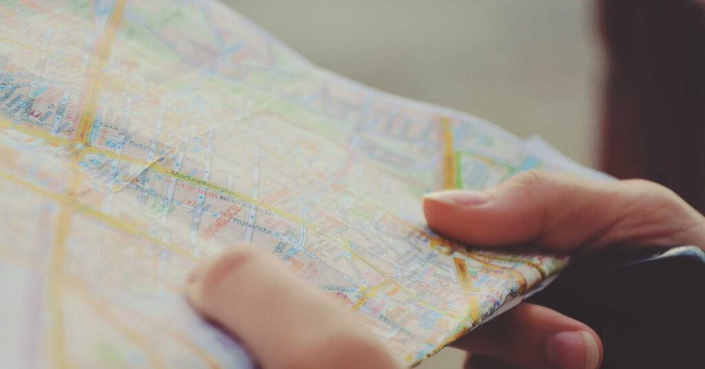 Close-up of hands holding a folded map, focusing on city streets and routesW