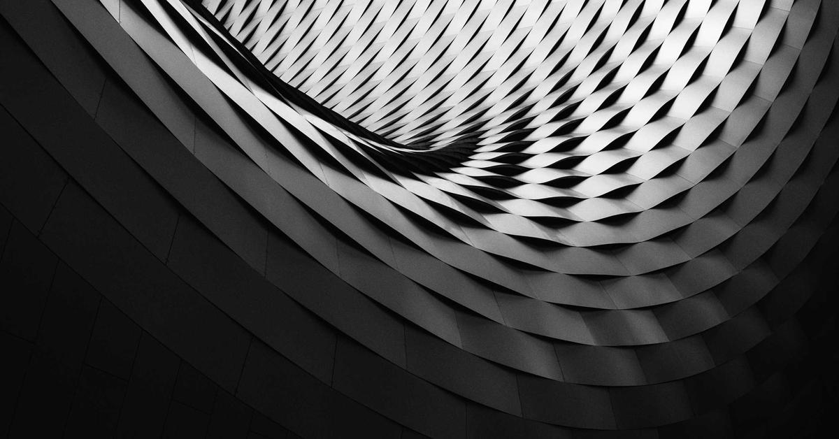 Abstract black-and-white spiraling architectural panels creating a curved tunnel effect in grayscale.