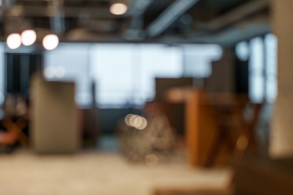 Blurred modern office interior with warm pendant lights and indistinct desks.